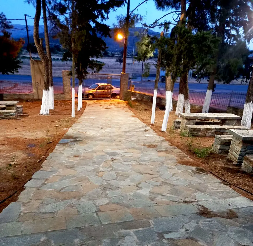 Πέτρινη διαδρομή ανάμεσα σε δέντρα με φωτιστικά εξωτερικού χώρου